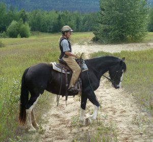 Birgit riding a training horse on the trail